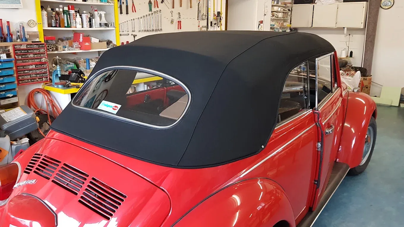 Capote nera montata su un Maggiolino cabriolet rosso, vista da dietro.