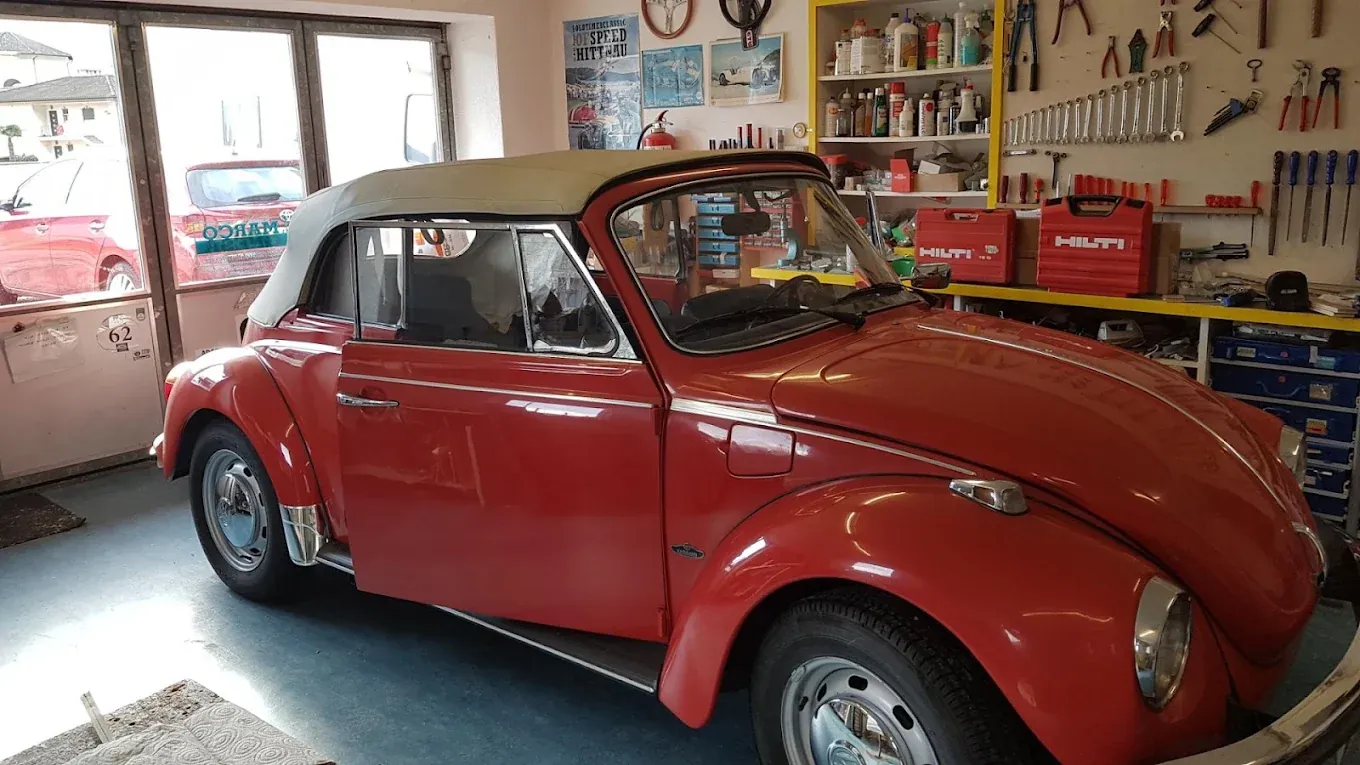 Maggiolino cabriolet rosso con capote in tela chiara appena montata, in laboratorio.