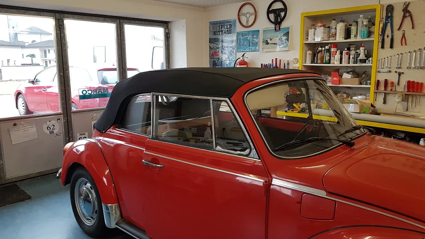 Interno del laboratorio: un'automobile cabriolet con la capote appena montata, davanti alla porta aperta sul piazzale.