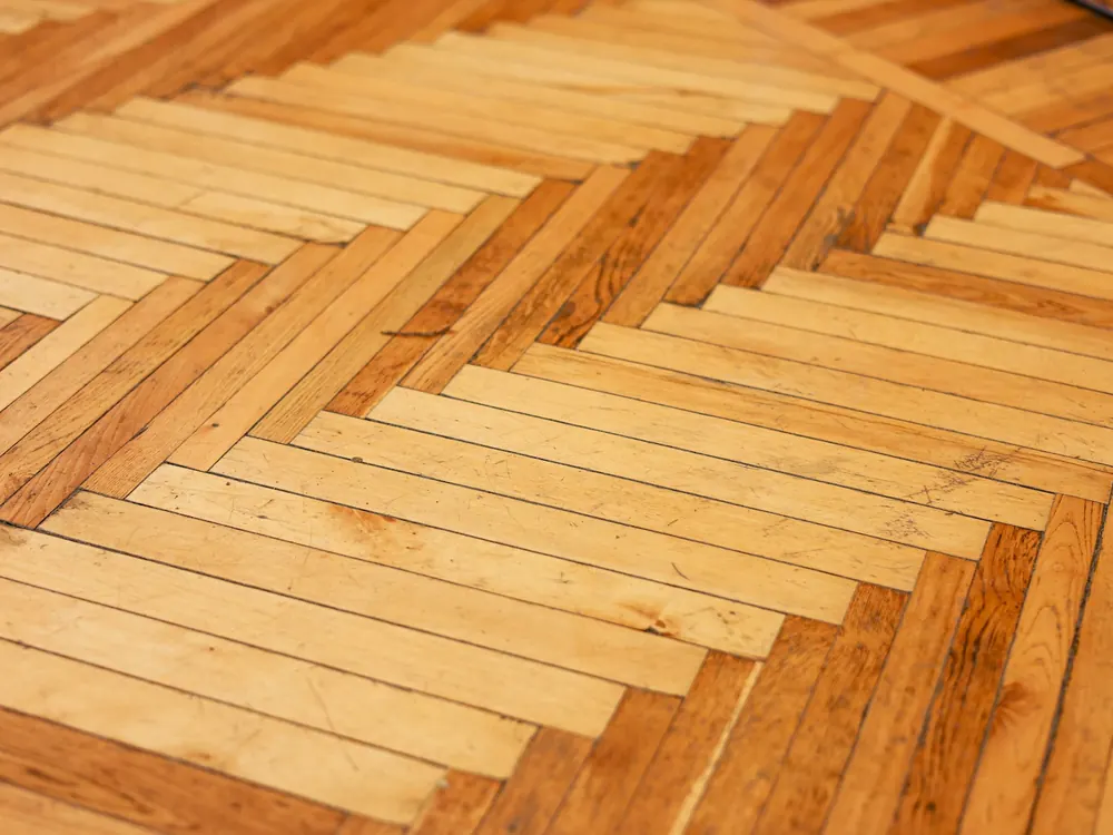 Pavimento in legno posato a spina di pesce, visto da vicino.